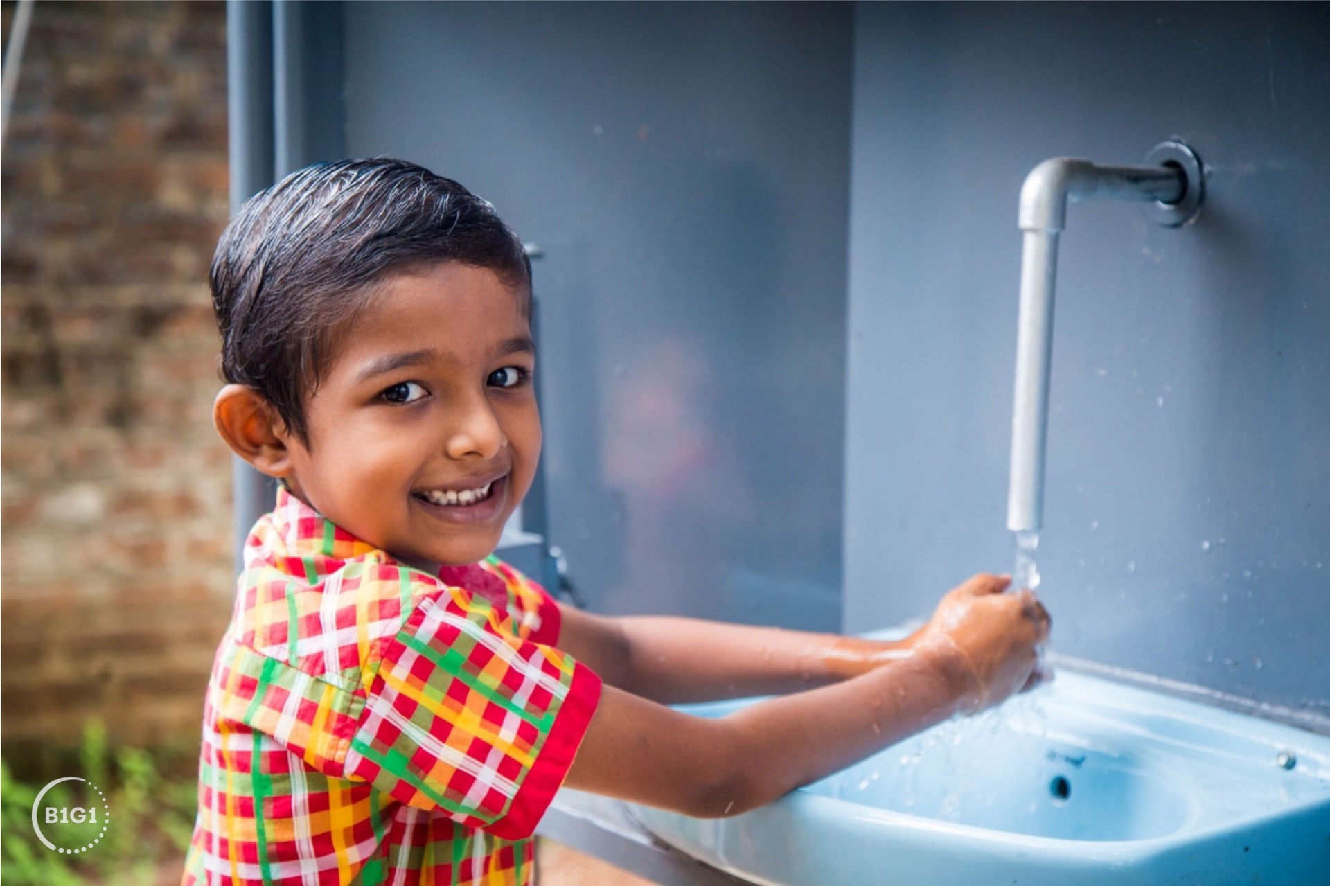 Child washing hands at a clean water station built through B1G1